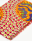 Close-up of folded Stories In The Sun 100% Cashmere Scarf displaying the vibrant red, yellow, and blue circular art pattern designed by Kaye White.