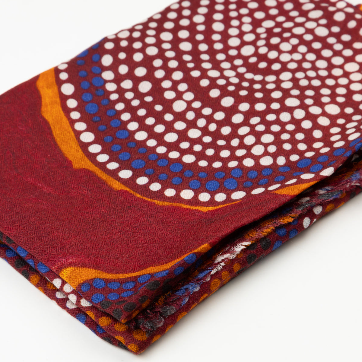 Close-up of folded Ants Nest 100% Cashmere Scarf displaying the detailed deep red and ochre Indigenous dot pattern designed by Emma Kerslake.