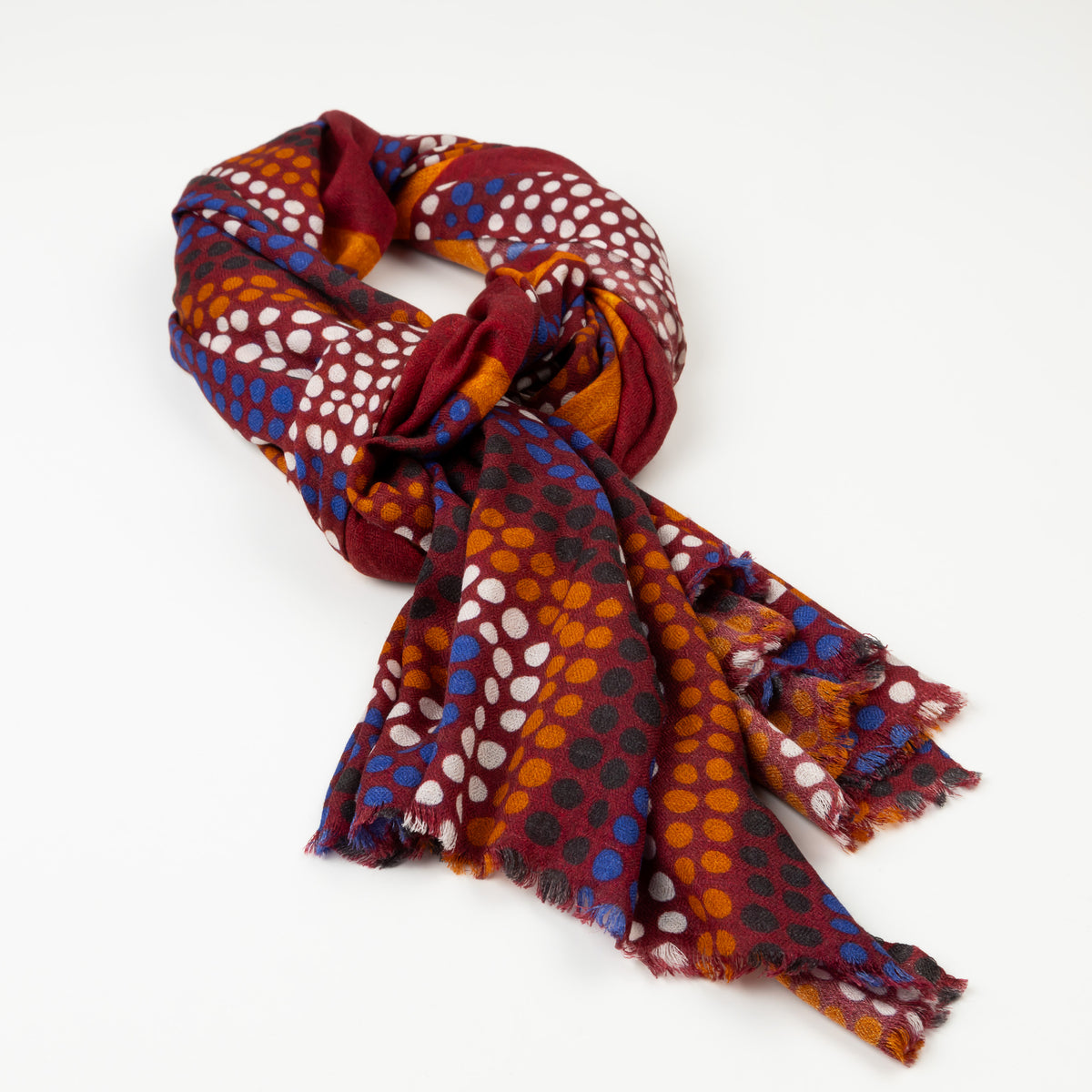 Kirrikin Ants Nest Luxury Cashmere Scarf styled in a loose knot, featuring rich burgundy, ochre, blue, and white Indigenous dot artwork by Emma Kerslake.