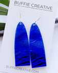 Bidi Blue Earrings on Buffie Creative card packaging, featuring elongated arch drops in vibrant electric blue with textured linework and pathway patterns on silver ear wires, designed by Buffie Punch.