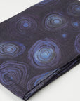 Close-up of folded 100% Cashmere Scarf displaying the detailed deep blue and purple concentric circle pattern designed by artist Helena Geiger.