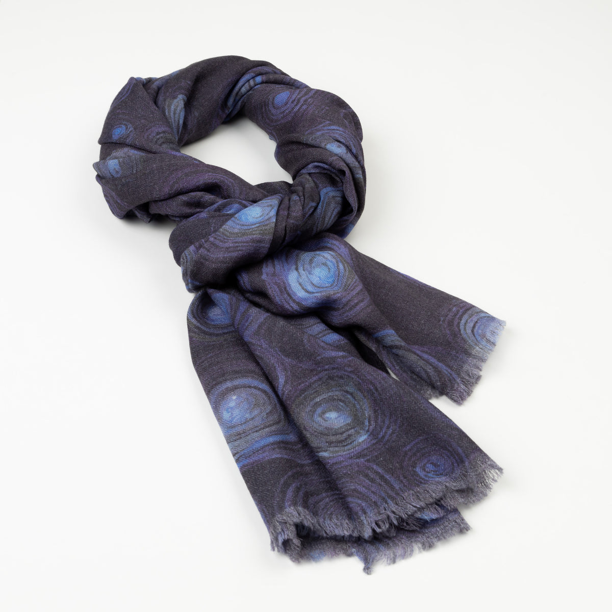 Kirrikin Luxury Cashmere Scarf styled in a loose knot on a white background, featuring dark blue and purple circular Indigenous artwork by Helena Geiger with frayed edges.
