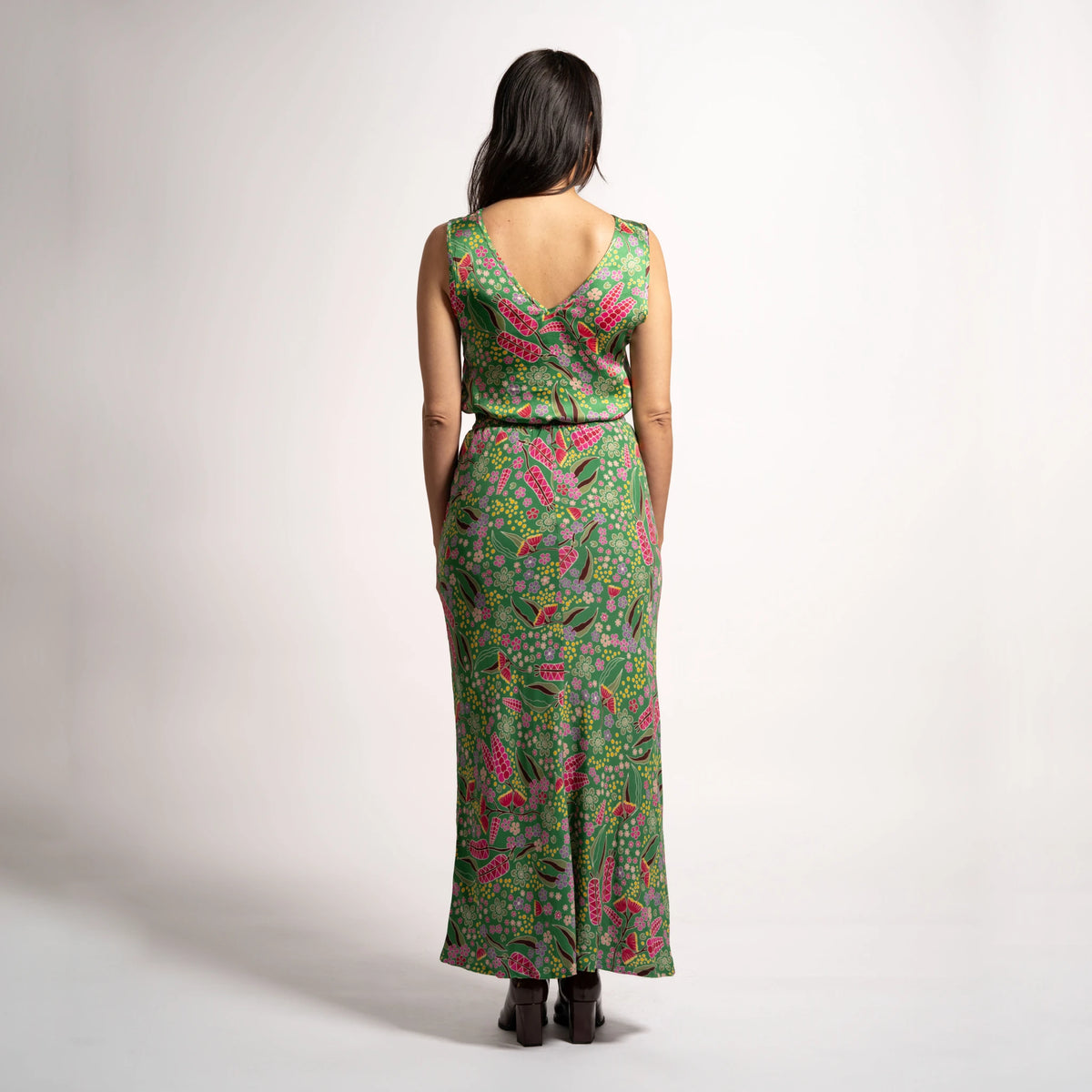 Full rear view of model wearing the green patterned Jenni maxi skirt styled with a sleeveless V-neck top.