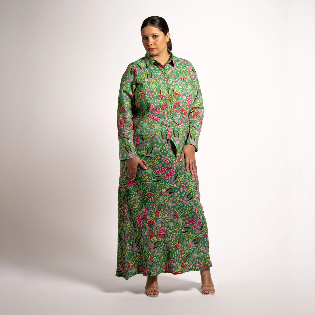 Front view of model wearing the green printed Jenni maxi skirt with a long sleeve button-up shirt set.