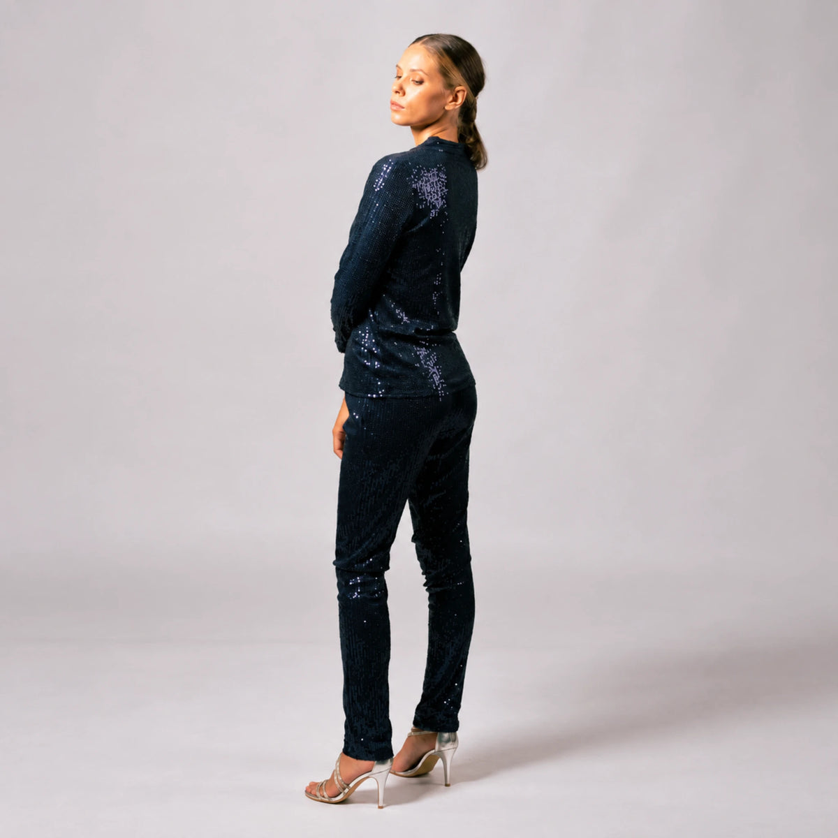 Side and back view of model wearing navy blue sequin pants with a matching sequin jacket.