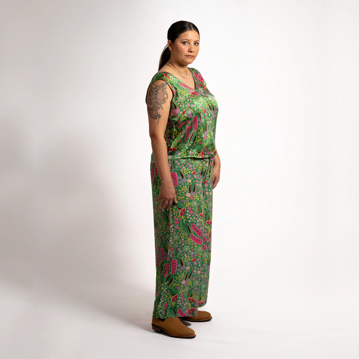 Full side profile view highlighting the flowing fit and vibrant Indigenous pattern of the green Sophie Pants Boodja.