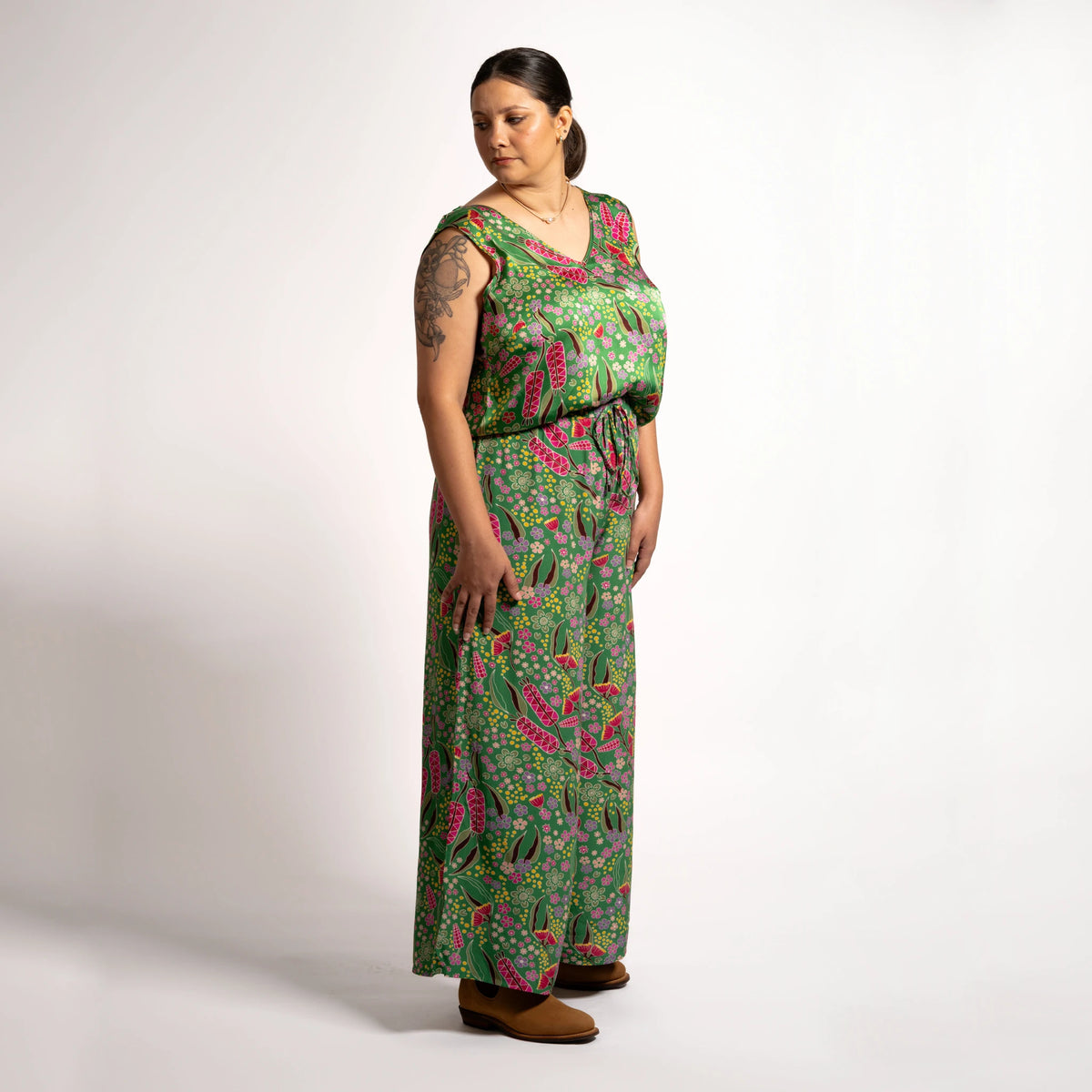Three-quarter side angle of model wearing relaxed-fit green wide-leg pants featuring Boodja floral print and comfortable elastic waistband.