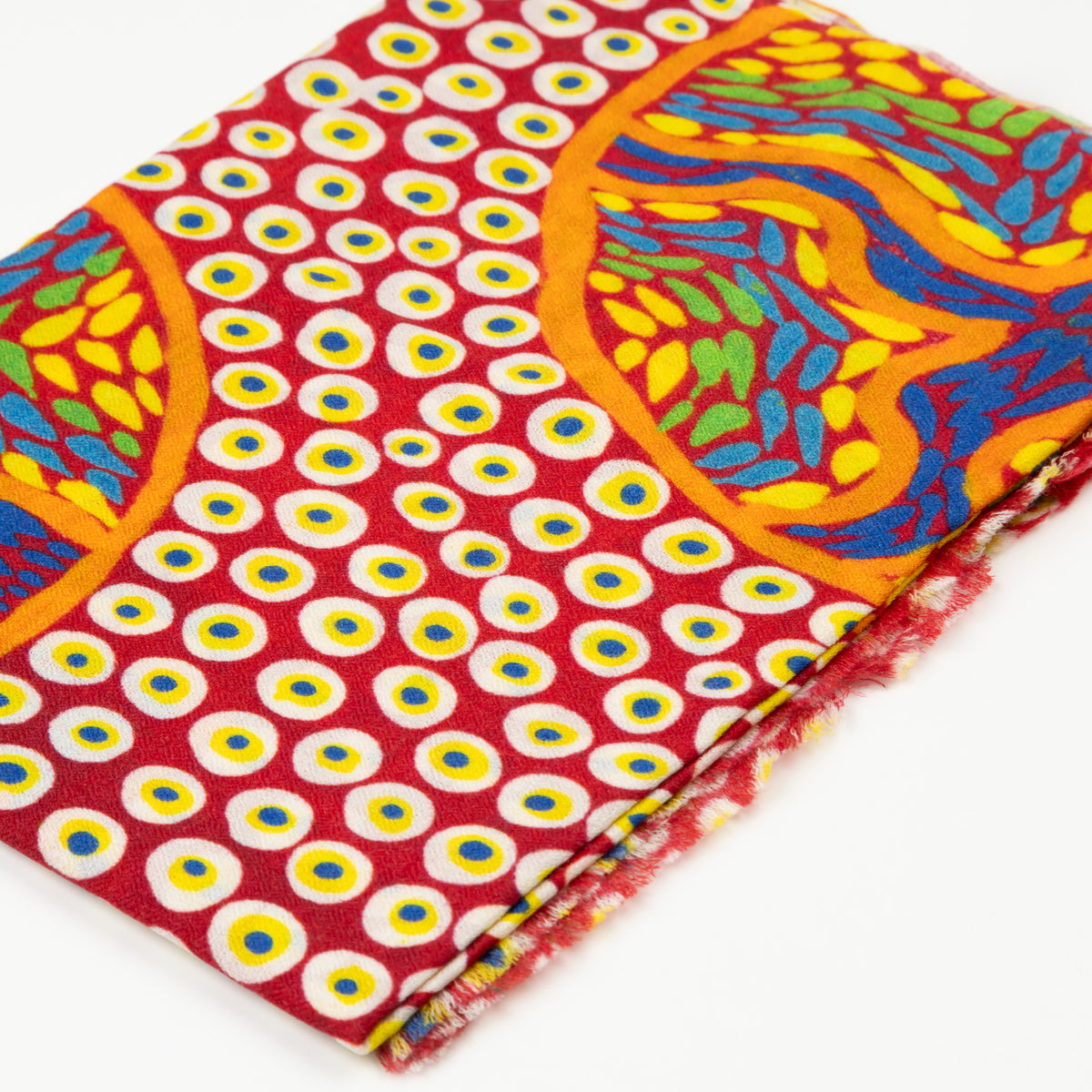 Close-up of folded Stories In The Sun 100% Cashmere Scarf displaying the vibrant red, yellow, and blue circular art pattern designed by Kaye White.
