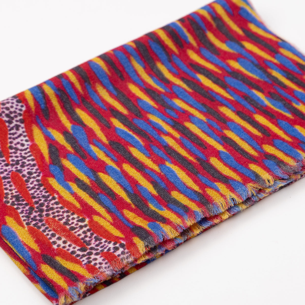 Close-up of folded Storms In The Pilbara 100% Cashmere Scarf displaying the vibrant red, blue, and yellow artwork designed by Kaye White.