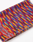 Close-up of folded Storms In The Pilbara 100% Cashmere Scarf displaying the vibrant red, blue, and yellow artwork designed by Kaye White.