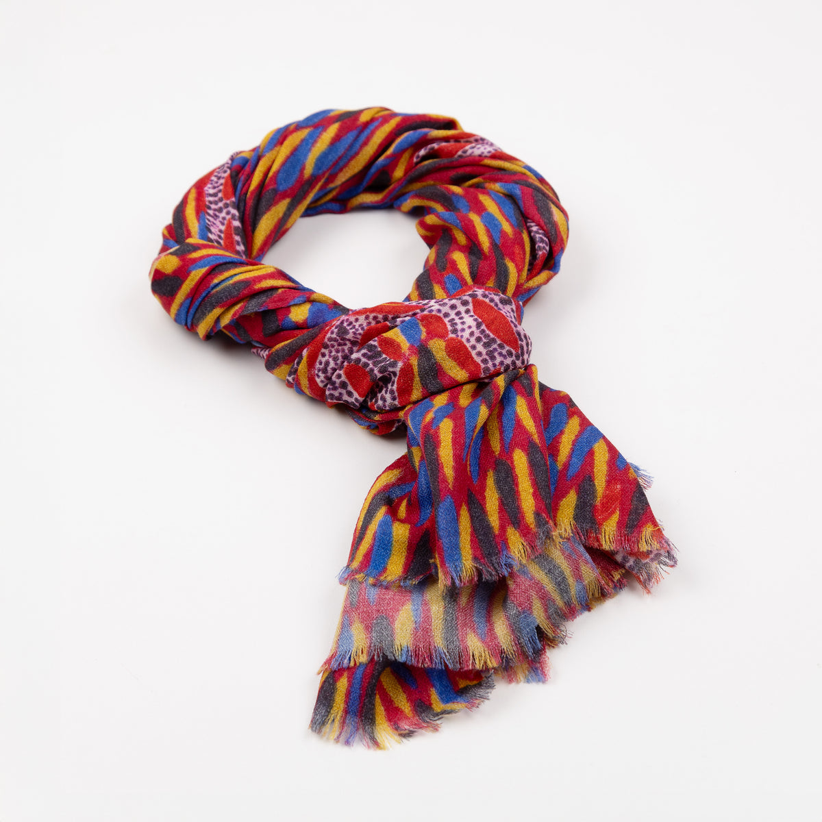 Kirrikin Storms In The Pilbara Luxury Cashmere Scarf styled in a loose knot on a white background, featuring red, yellow, and blue Indigenous artwork patterns with naturally frayed edges.